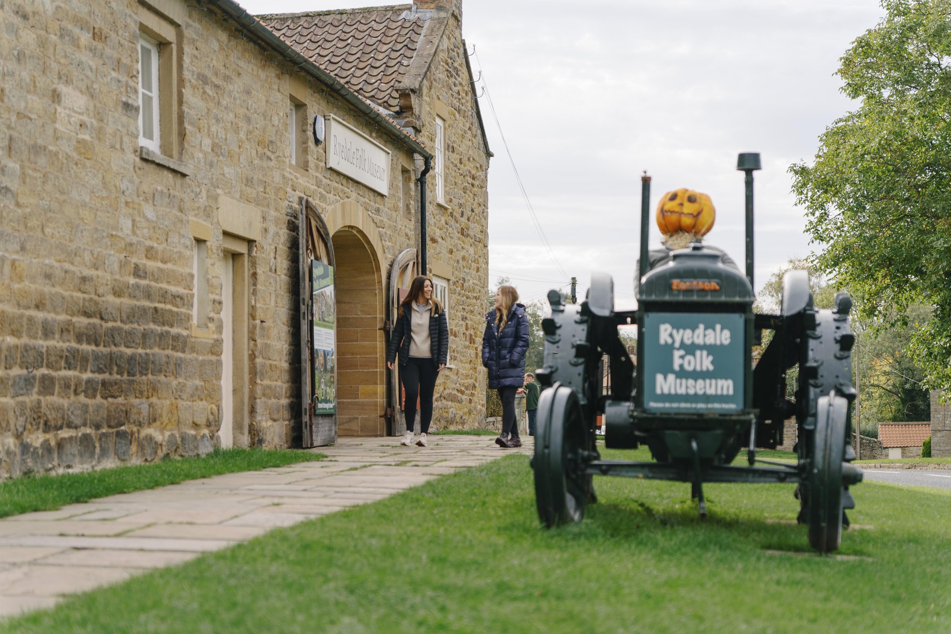 Two people walking past a tractor outside the museum